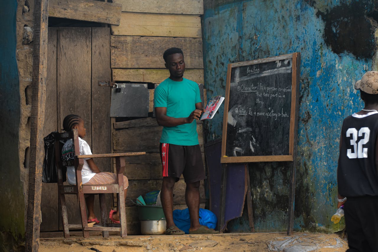 about-01 A teacher conducts an outdoor class for children in Monrovia, showcasing community education.